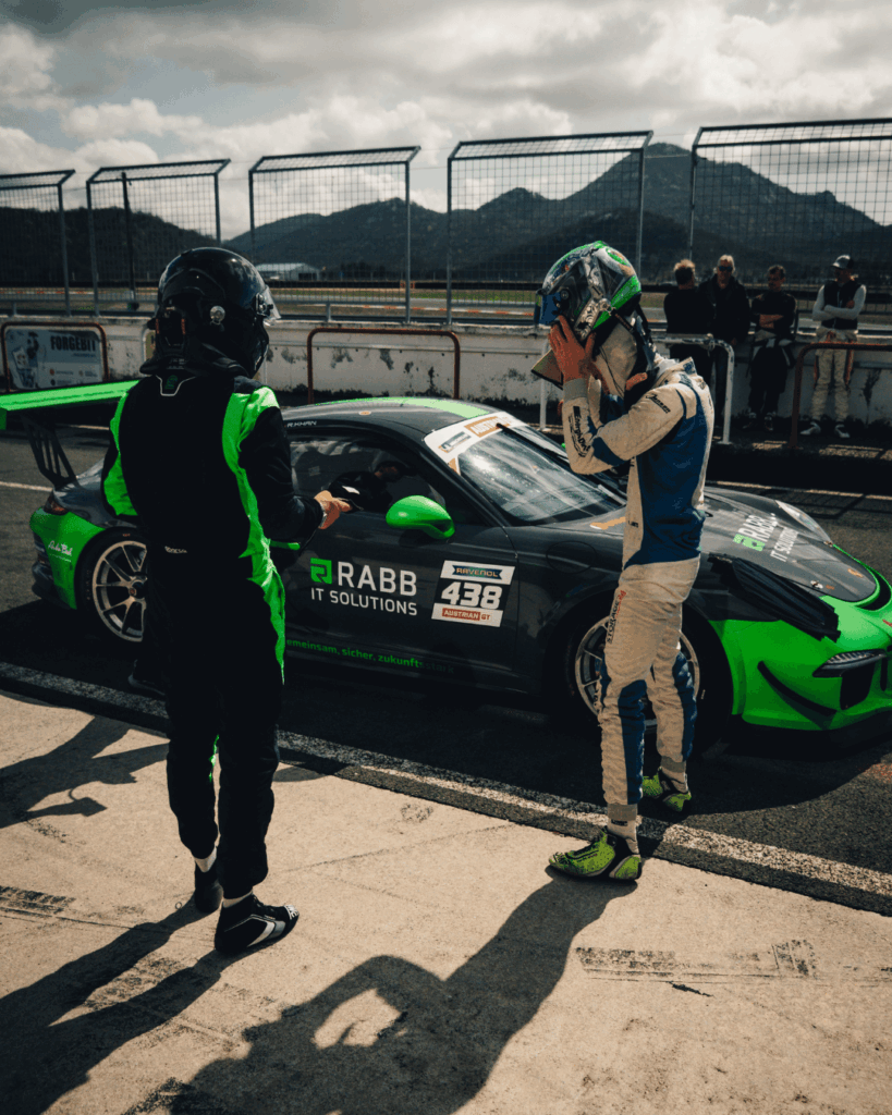 Zwei Rennfahrer neben einem Porsche 911 GT3 Cup von RABB in der Boxengasse